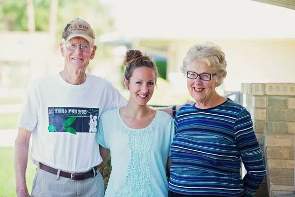 Three people smiling at the camera outside.