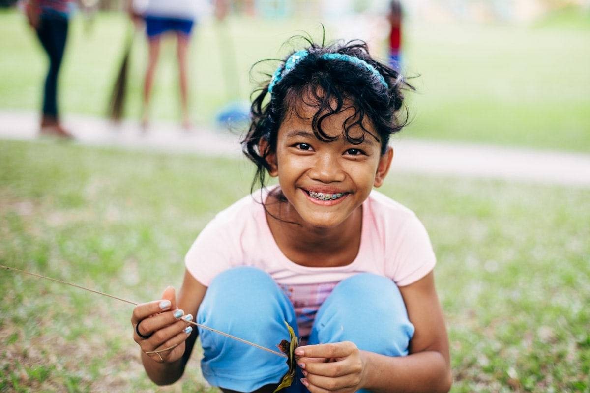 Young girl with headband smiling at camera.