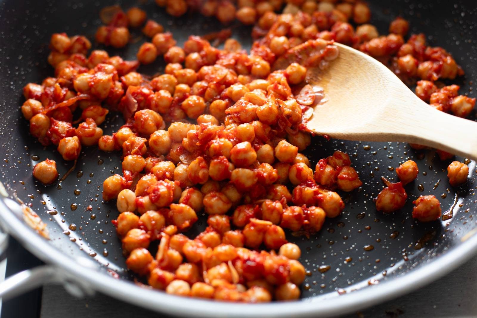 Chickpeas and tomato paste in a skillet.