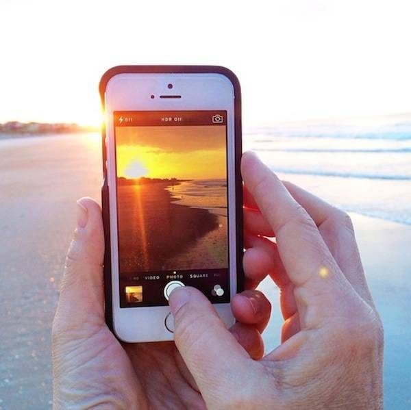 Iphone taking a photo of the sunrise.