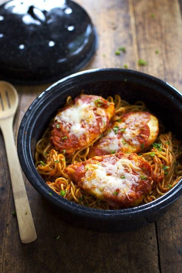 Chicken Pizzaiola in a black dish with a wooden spoon.