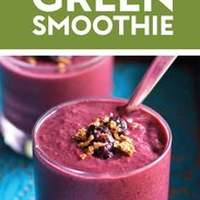 Berry green smoothie in a glass with granola on top.