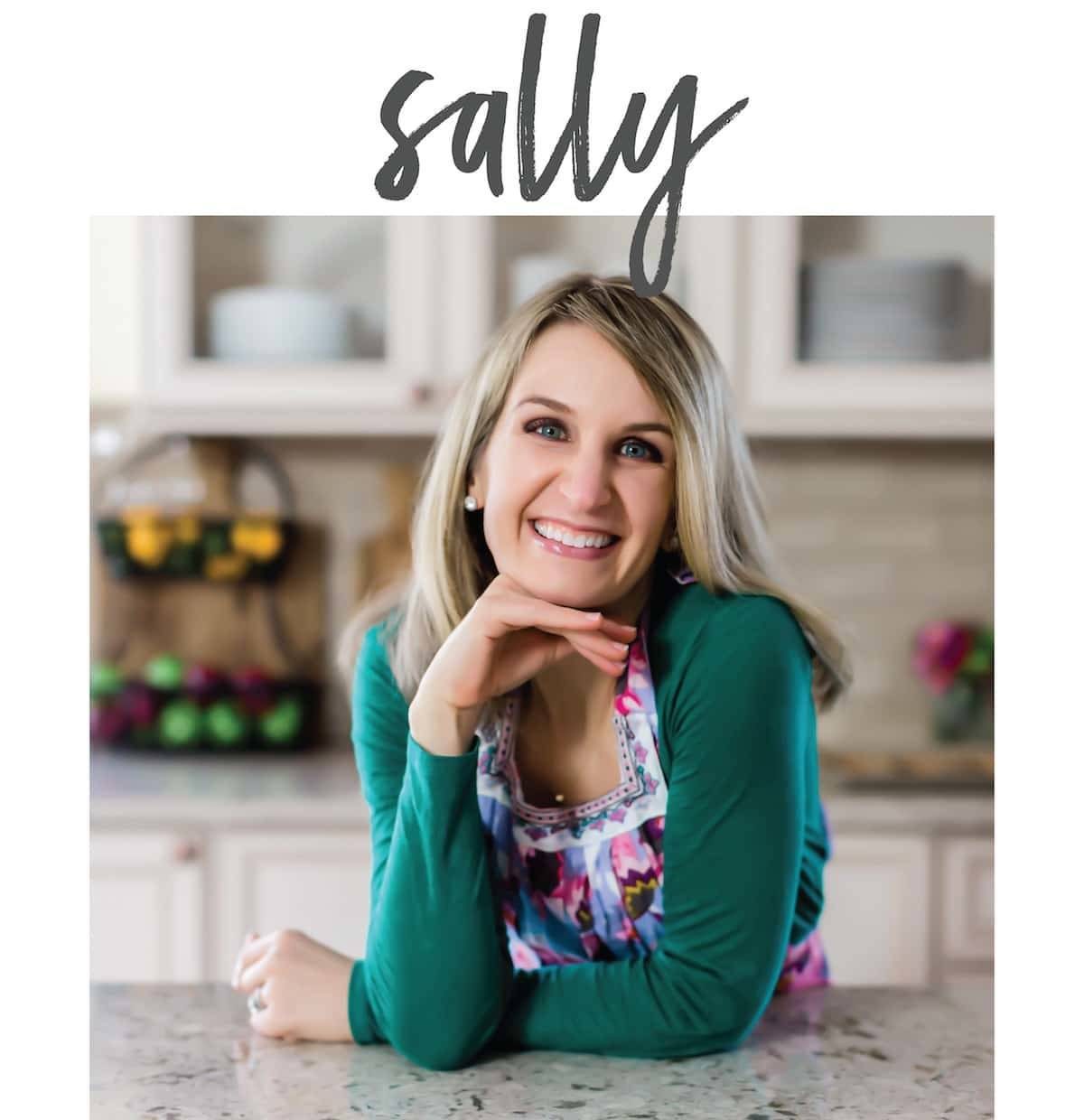 Sally smiling and resting on her elbows in her kitchen.