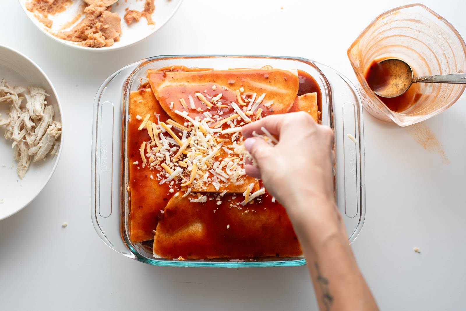 Sprinkling cheese on top of enchilada casserole.