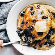 Blueberry pancakes on a plate with syrup and butter.
