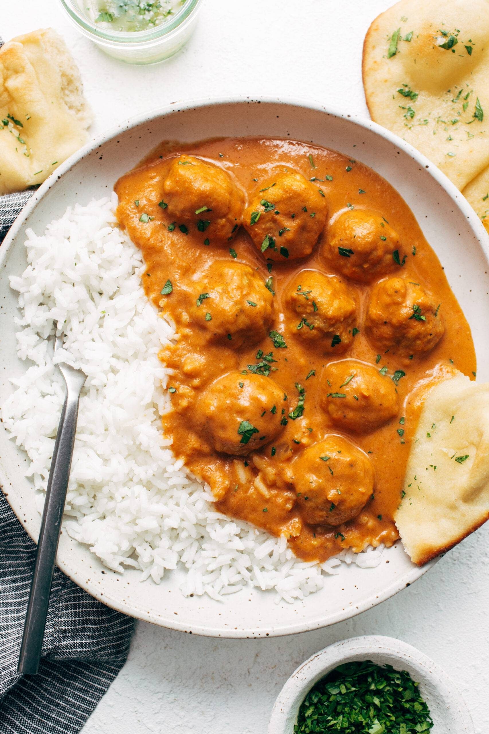 Butter chicken meatballs in a bowl with rice and naan.