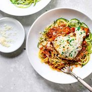 Chicken parmesan on a plate of zucchini noodles.