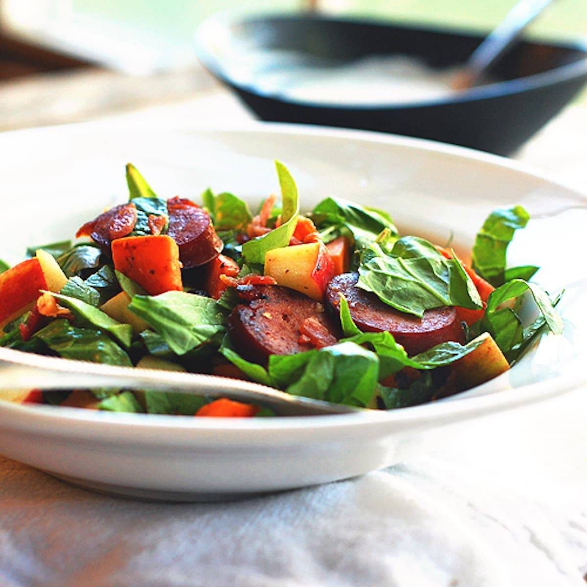 Harvest salad with sweet potato, spinach, turkey kielbasa, bacon, apples, and topped with a creamy homemade maple dressing.