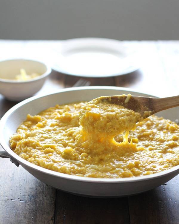 Squash curry quinoa in a bowl with a wooden spoon.
