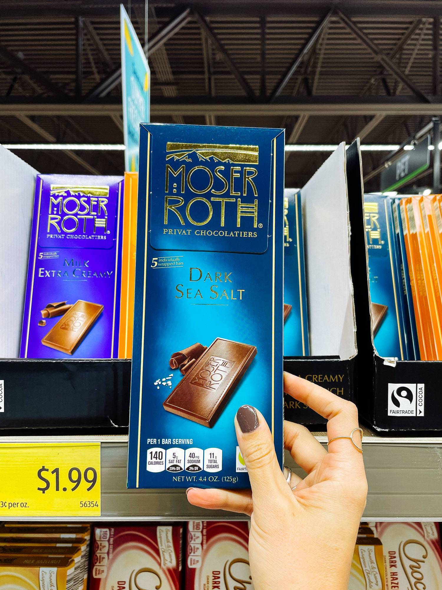 White hand holding dark chocolate bar from ALDI.