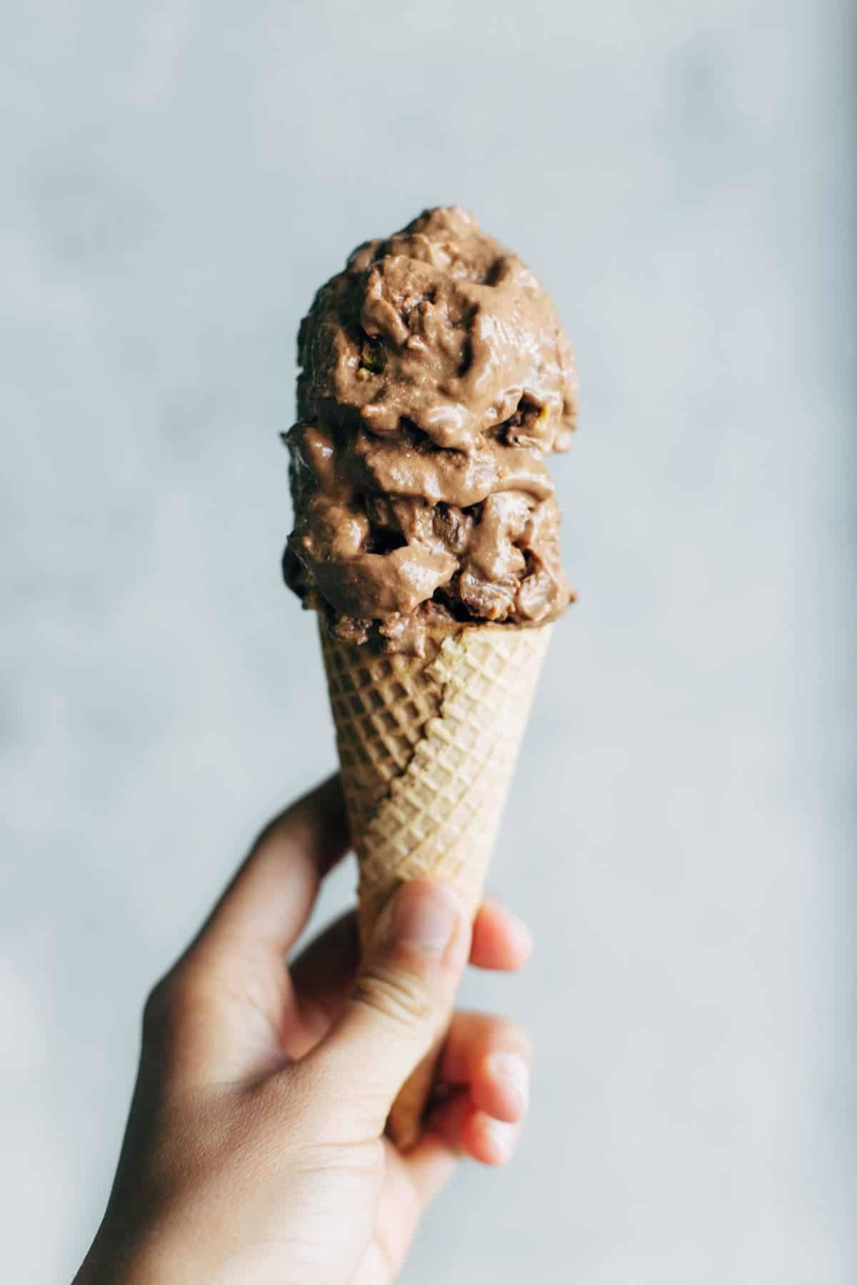 Hand holding a cone of nice cream.